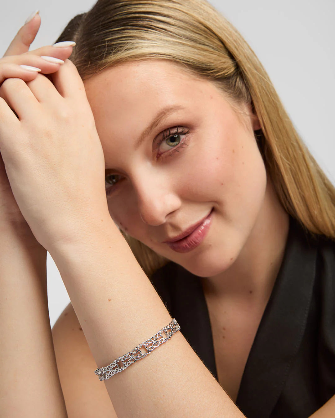 Woman wearing a silver Celtic knot bracelet with a neutral background